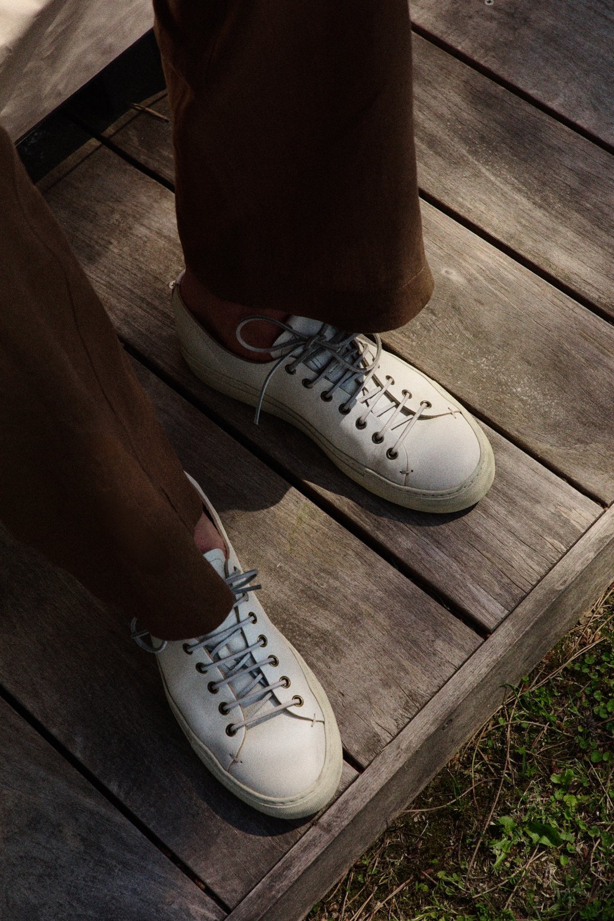 Tanino sneakers in cream leather worn on a wooden deck